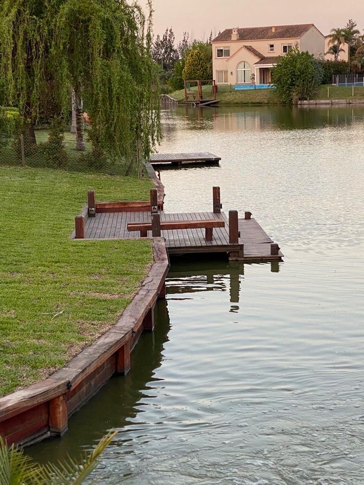 two wooden benches sitting on the side of a body of water next to a dock