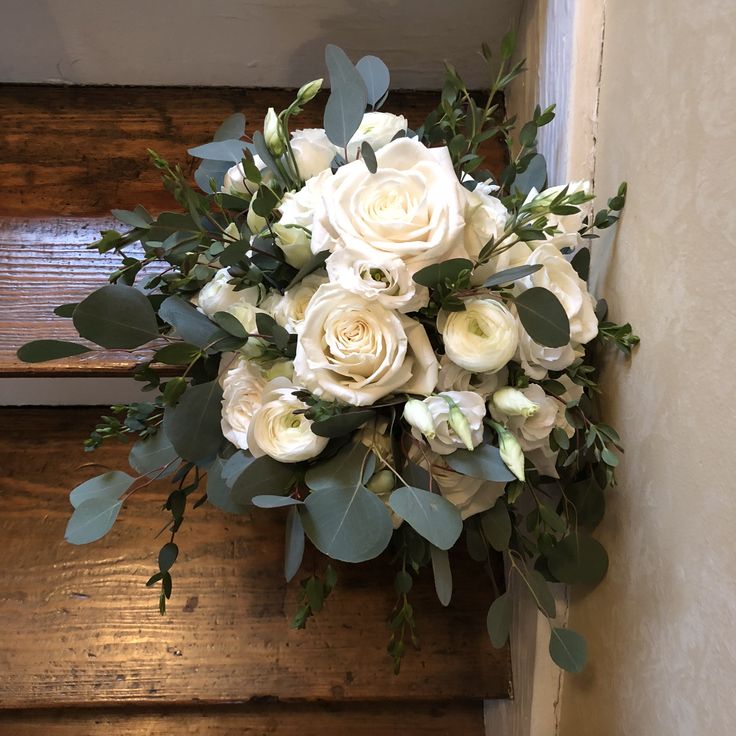 a bouquet of white flowers sitting on top of a wooden step