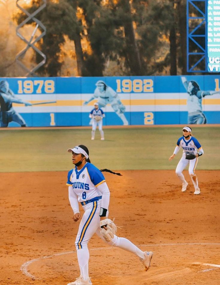 some baseball players are playing baseball on a field and one is running to the base