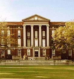 an old brick building with columns and pillars on the front, surrounded by green grass