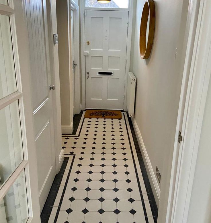 a hallway with black and white tile flooring next to a door in a house