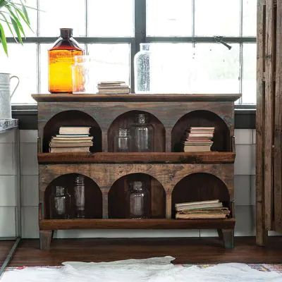 an old wooden shelf with jars and books on it in front of a large window