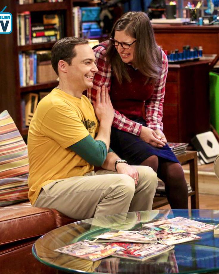 the young man and woman are sitting together in front of a table with magazines on it