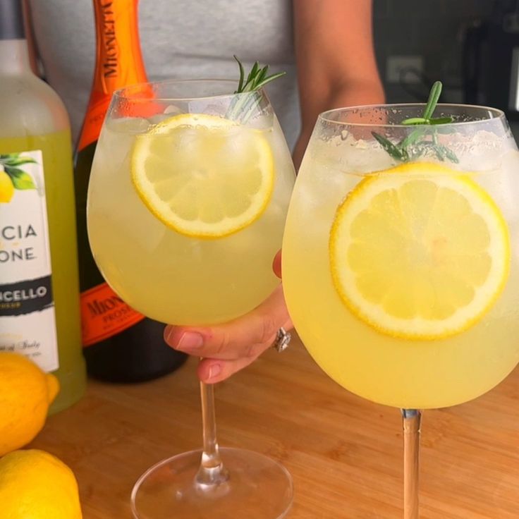 two glasses filled with lemonade sitting on top of a wooden table