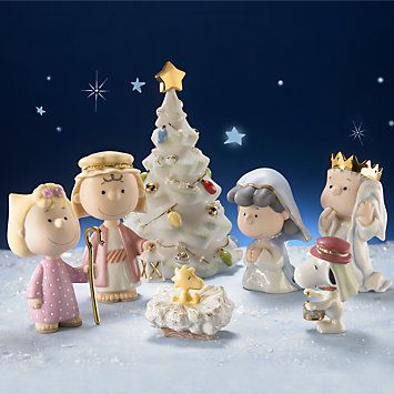 a group of small figurines standing next to each other in front of a christmas tree