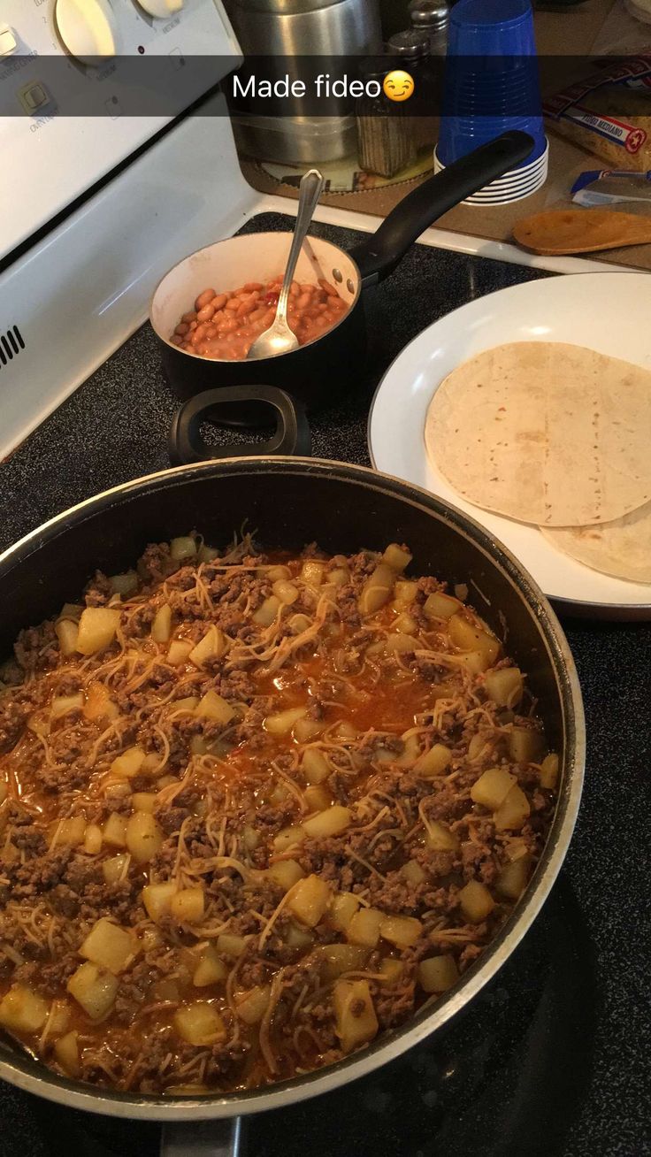 a pan filled with food sitting on top of a stove next to a plate and bowl