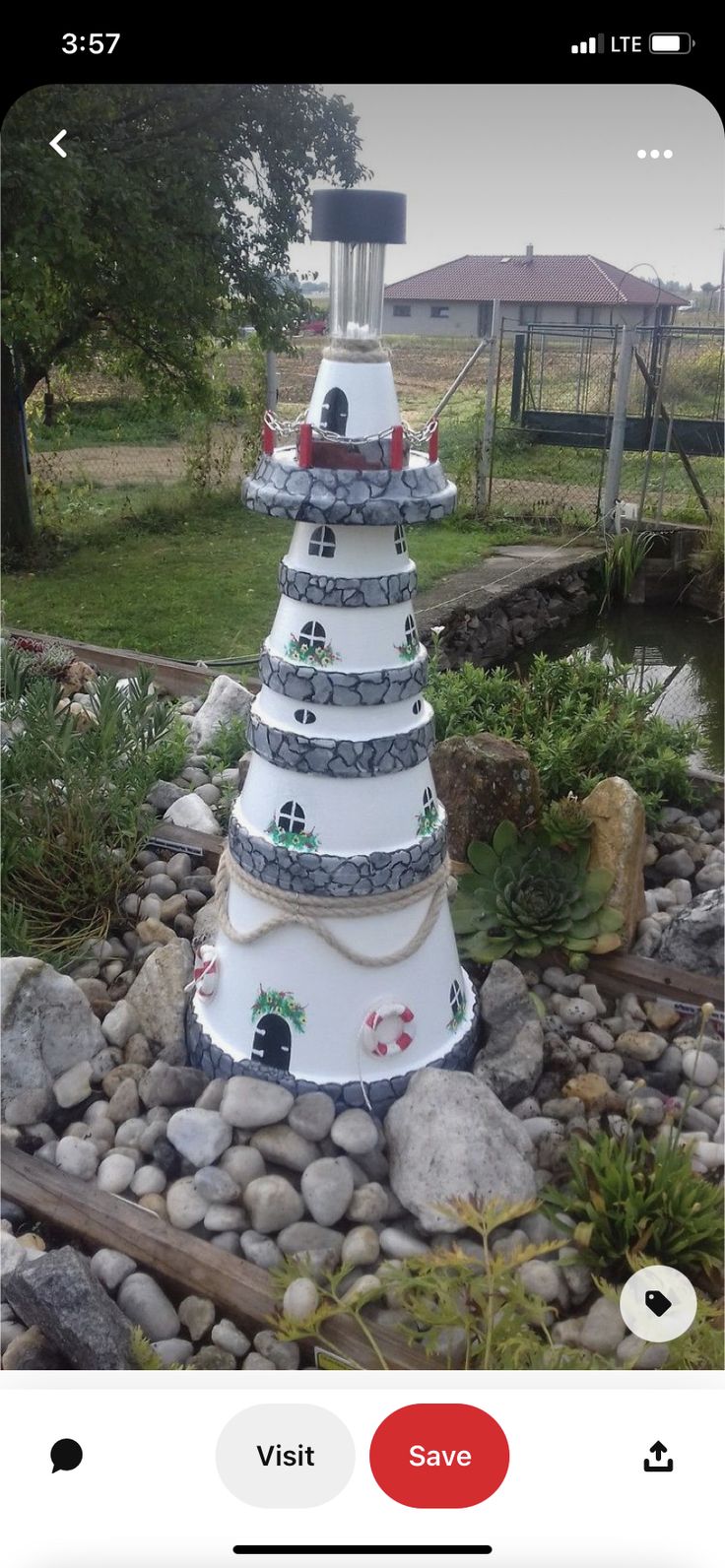 a garden with rocks, plants and a light pole in the middle on top of it