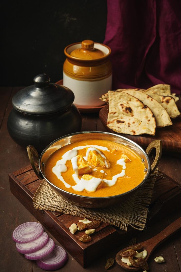 a bowl filled with soup next to some pita bread and other food items on a table