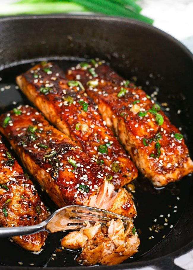 a pan filled with meat and sauce on top of a table next to green onions