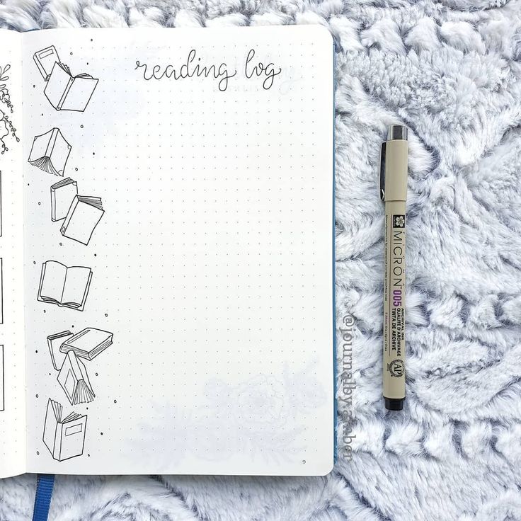 an open notebook with some drawings on it and a pen laying next to the pages