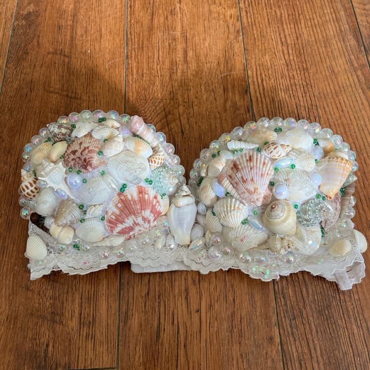 two decorative seashells are sitting on a wooden floor with beaded trimming