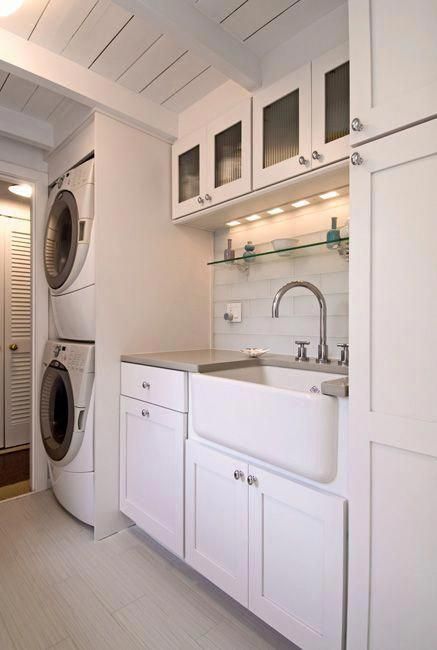 a washer and dryer in a small room with white cabinets on the walls