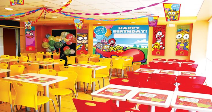 the interior of a children's birthday party with bright yellow chairs and red tables