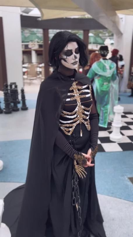 a man in skeleton makeup and costume standing on a checkered floor