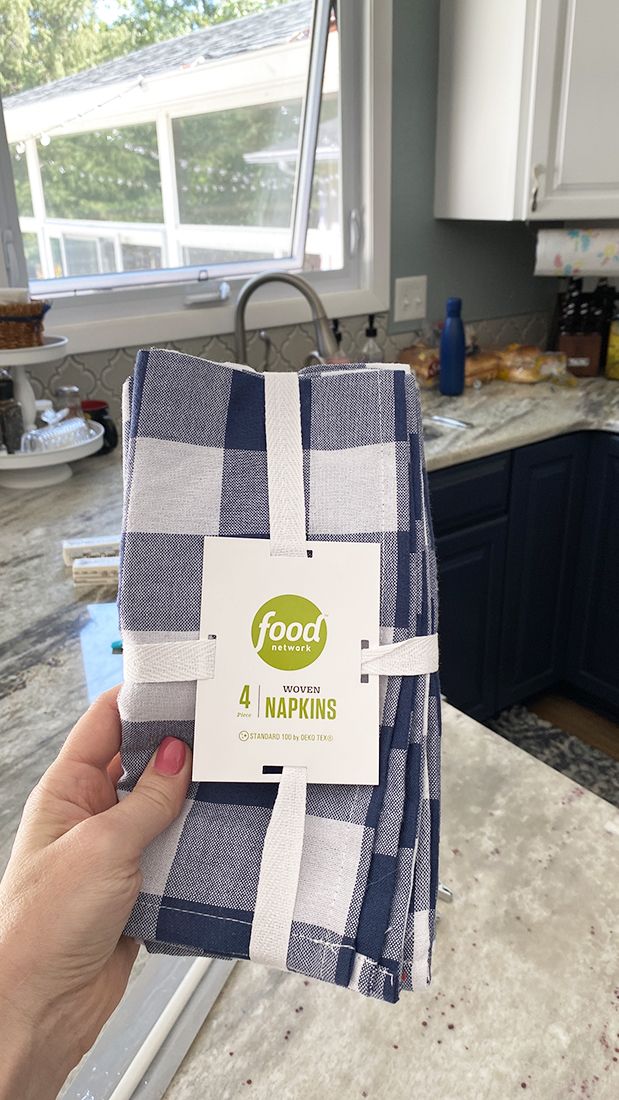 a person holding up two napkins in a kitchen