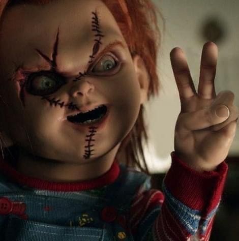 a creepy doll with red hair making the peace sign