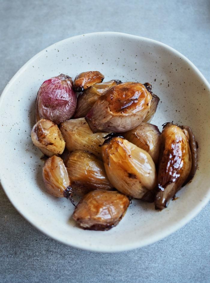 a white bowl filled with roasted onions on top of a table