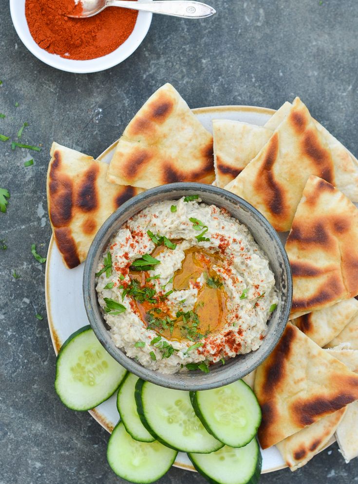 cucumber and pita chips with hummus on a plate next to dipping sauce