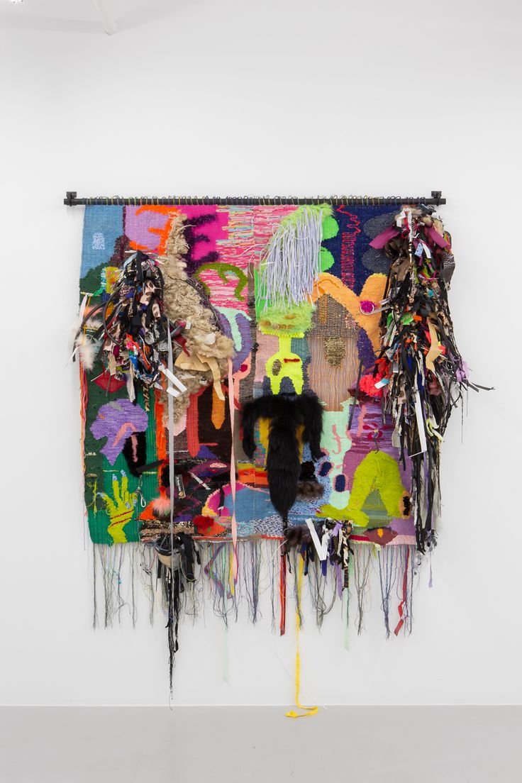 an art piece hanging on the side of a wall with multiple pieces of fabric attached to it