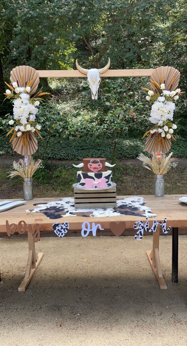 a wooden table topped with a cake and vases filled with flowers on top of it