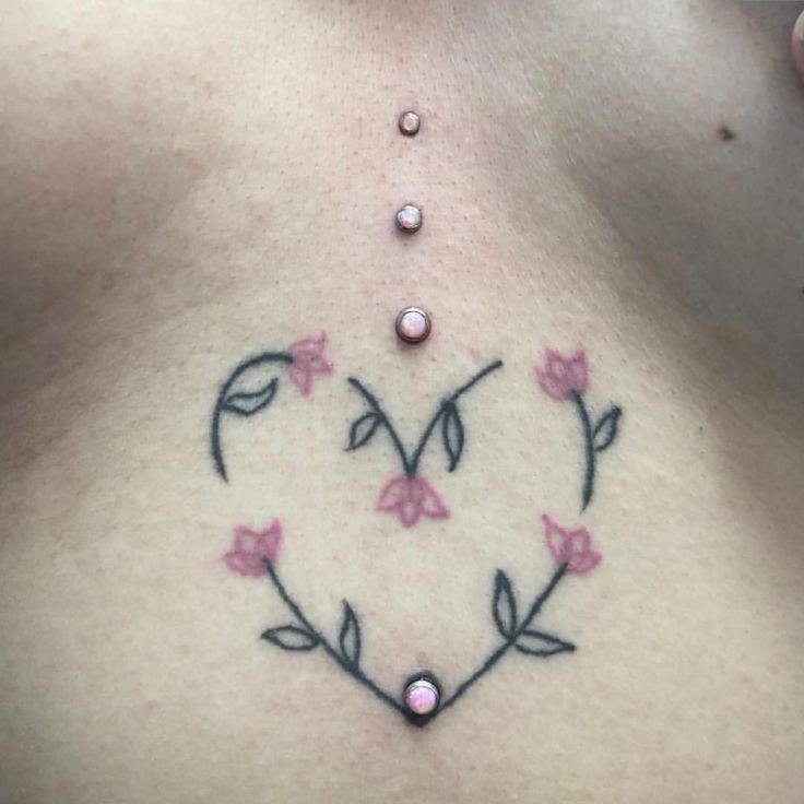 a woman's chest with pink flowers and leaves in the shape of a heart