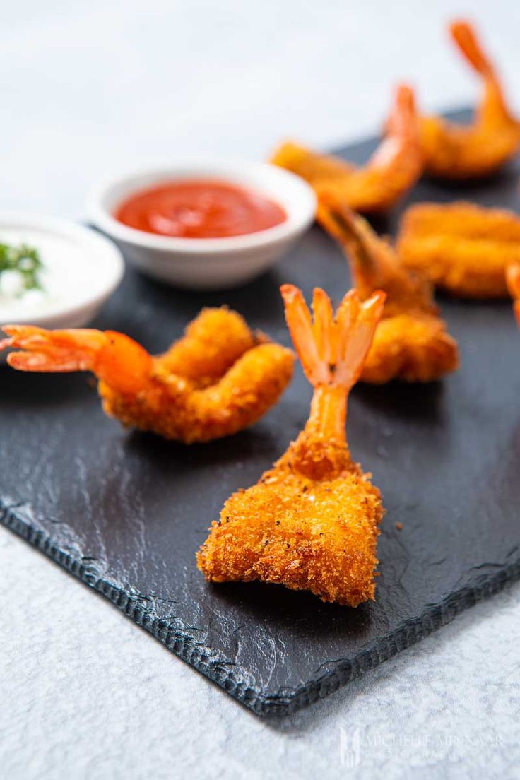 fried shrimp sticks with dipping sauce on a slate board