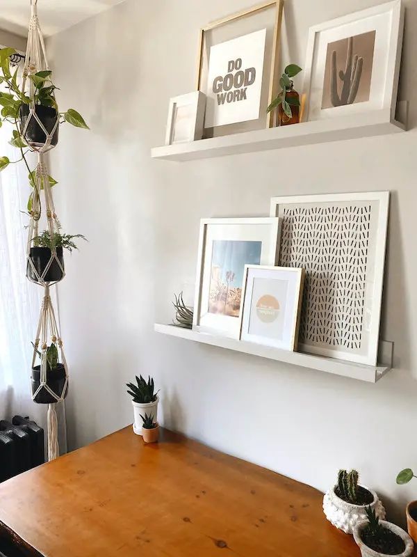 some plants are hanging on the wall above a wooden table