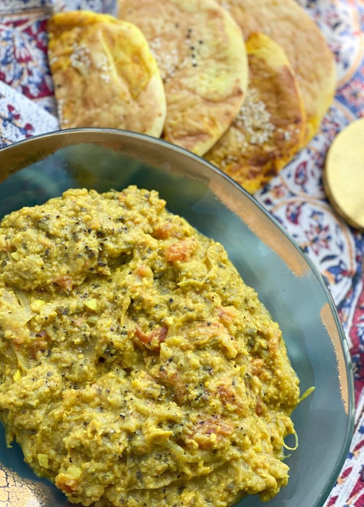 a bowl filled with green food next to tortilla chips on top of a table