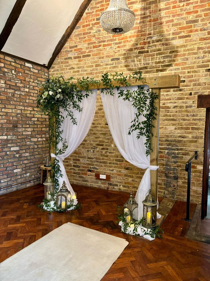 an indoor ceremony setup with white drapes and greenery