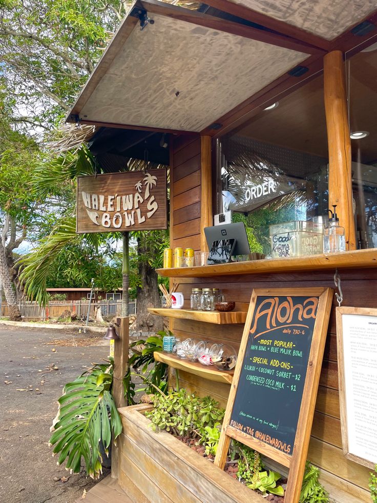 the outside of a restaurant with plants and signage