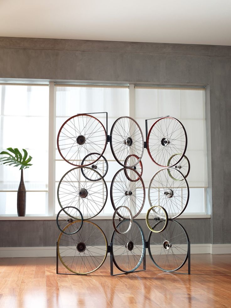 there is a sculpture made out of bicycles on the floor in front of two windows