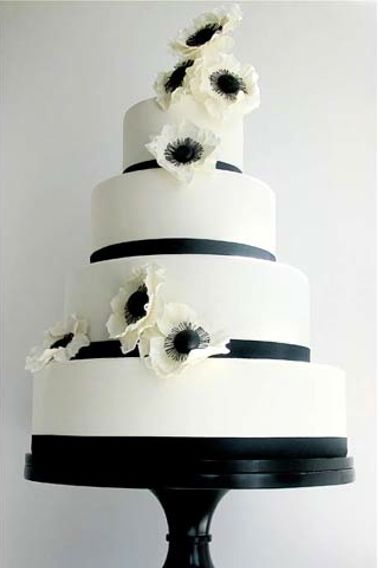 a white and black wedding cake with flowers on top