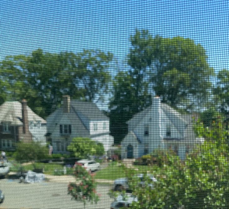 the view from an apartment window shows houses and trees