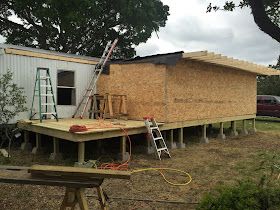 a house being built in the middle of a yard with a ladder on it's side