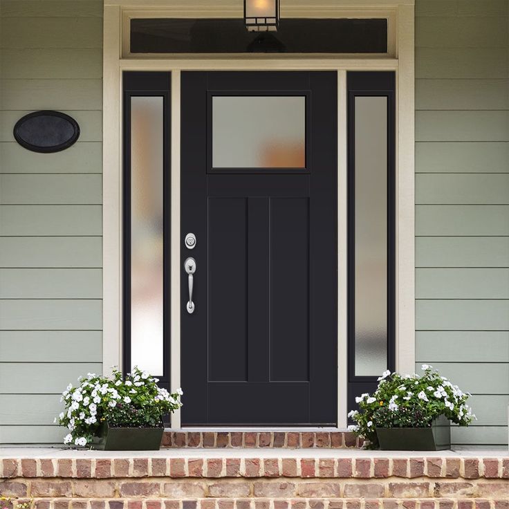 a black front door with two planters on the steps and a light above it