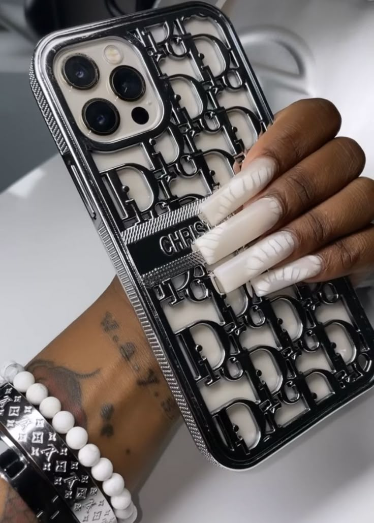 a woman's hand holding an iphone case with white nails