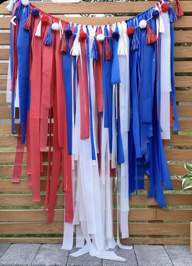 red, white and blue streamers are hanging from a wooden slatted fence