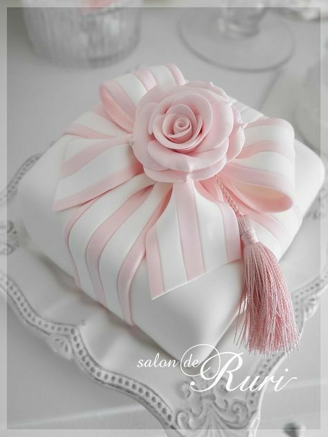 a white cake with pink ribbon and a rose on top