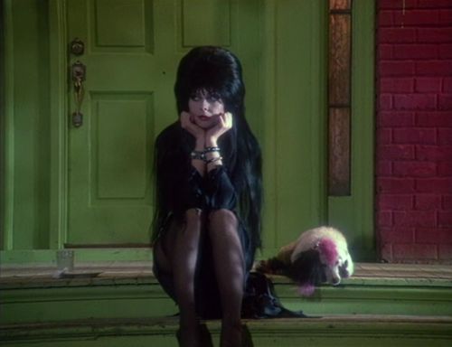 a woman with long hair sitting on a step next to a panda in front of a green door