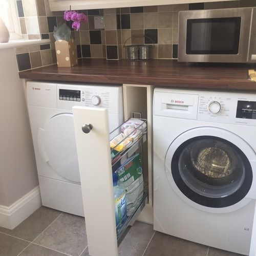 a washer and dryer in a small room with tile flooring on the walls