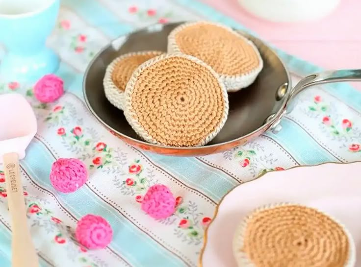 three crocheted cookies sitting in a pan on a table with utensils