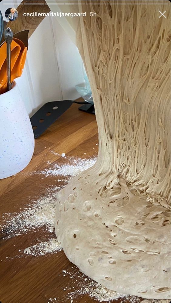 a person is making some food on the floor in front of a large tree stump