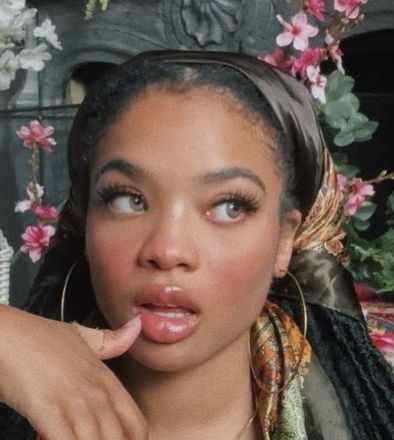 a woman sticking her tongue out in front of flowers