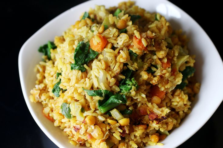 a white bowl filled with rice and veggies on top of a black table