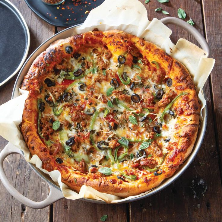 a pizza sitting on top of a pan covered in cheese and toppings next to other dishes