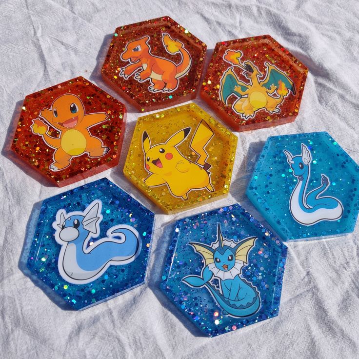 six different pokemon coasters sitting on top of a white cloth covered table with sequins