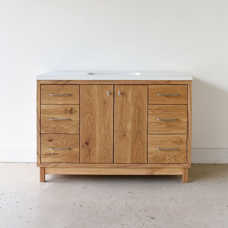 a bathroom vanity with two sinks and wooden cabinetry on the top, against a white wall