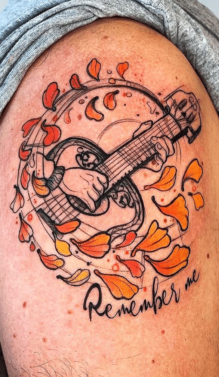 a man with a guitar tattoo on his arm and chest, in the shape of an orange flower