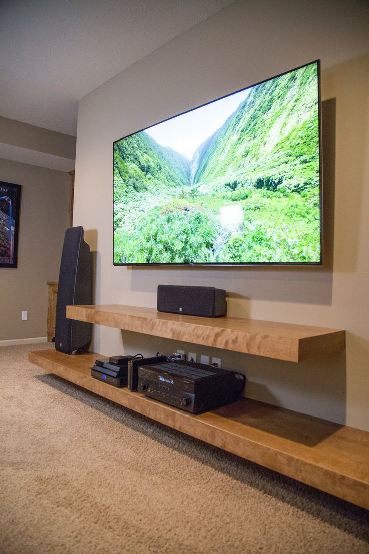 a flat screen tv mounted to the side of a wall next to a sound system