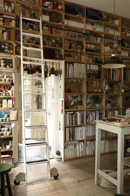 a room filled with lots of books and shelves next to a white table in front of a doorway